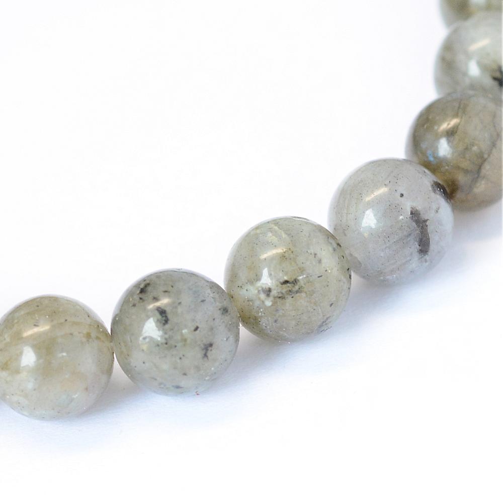 zoomed in section of smooth round grade b labradorite stone bead strand over white background. 