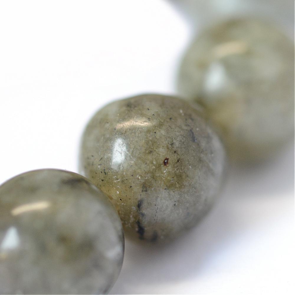 zoomed in section of single smooth round grade b labradorite stone bead on strand over white background. 