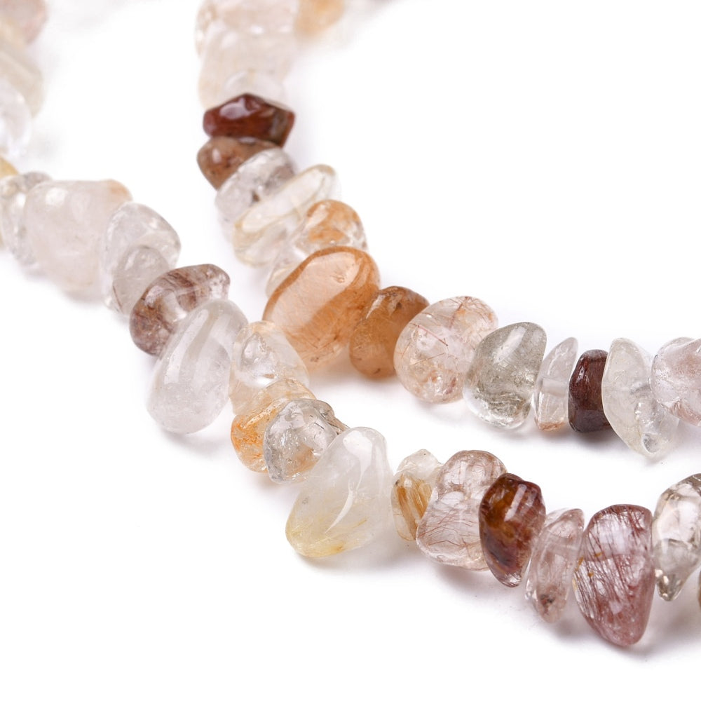 zoomed in sections of multi-color rutilated quartz chip bead strands over white surface. 