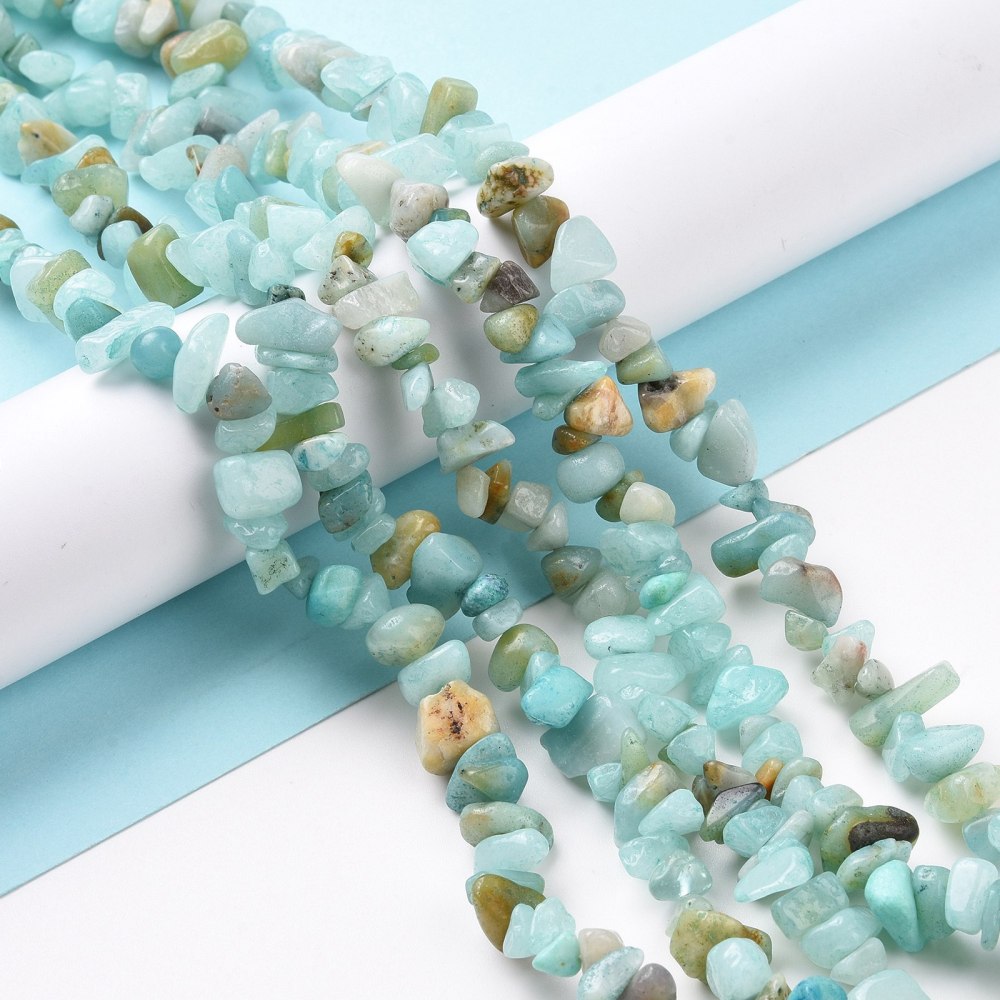 natural flower amazonite chip bead strands draped over white cylinder form onto light blue and white surface. 