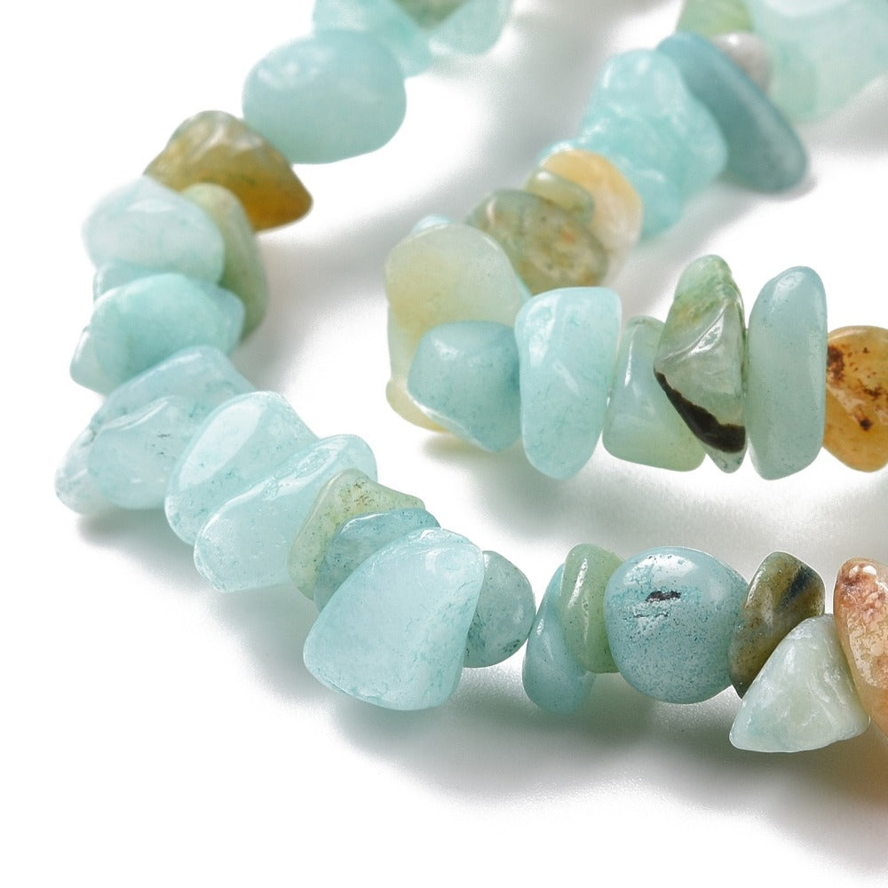 zoomed in sections of natural flower amazonite chip bead strand over white surface. 