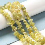 four lemon jade chip bead strands draped over white cylinder onto light blue and white surface. 