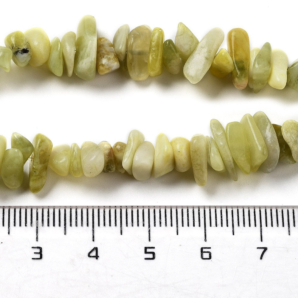 zoomed in sections of lemon jade chip bead strands displayed above a ruler over white background. 