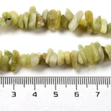 zoomed in sections of lemon jade chip bead strands displayed above a ruler over white background. 