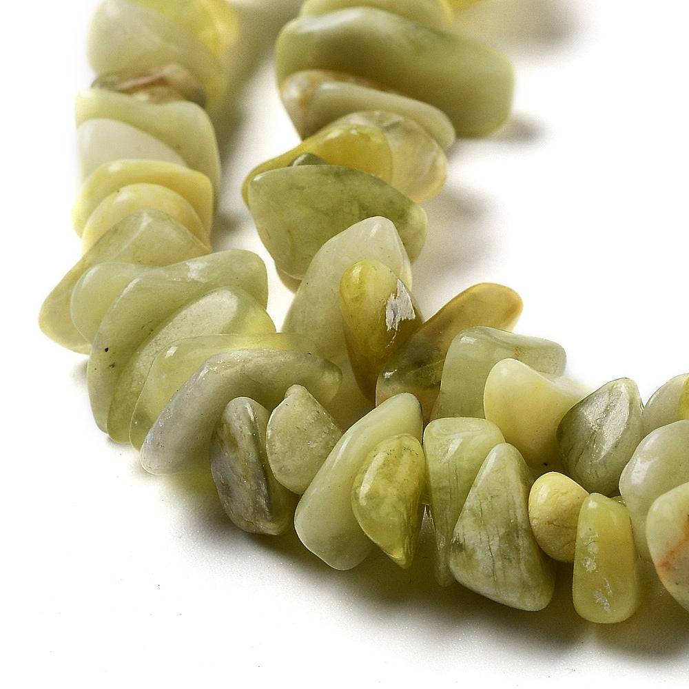 zoomed in sections of lemon jade chip bead strands over white surface. 