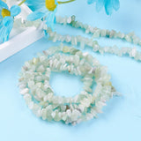 multiple strands new jade chip bead strands displayed over light blue surface with a white tray and bright blue daisy flowers peeking in from the corner.
