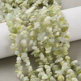 six new jade chip bead strands draped over white cylinder onto light grey felted surface. 