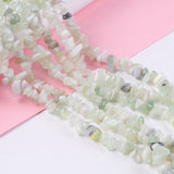 six new jade chip bead strands draped over white cylinder onto light pink and white surface. 