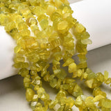 six strands of olive jade chip beads draped over white cylinder onto light grey felted surface. 