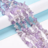 five lavender amethyst chip bead strands draped over white cylinder onto light blue and white surface. 