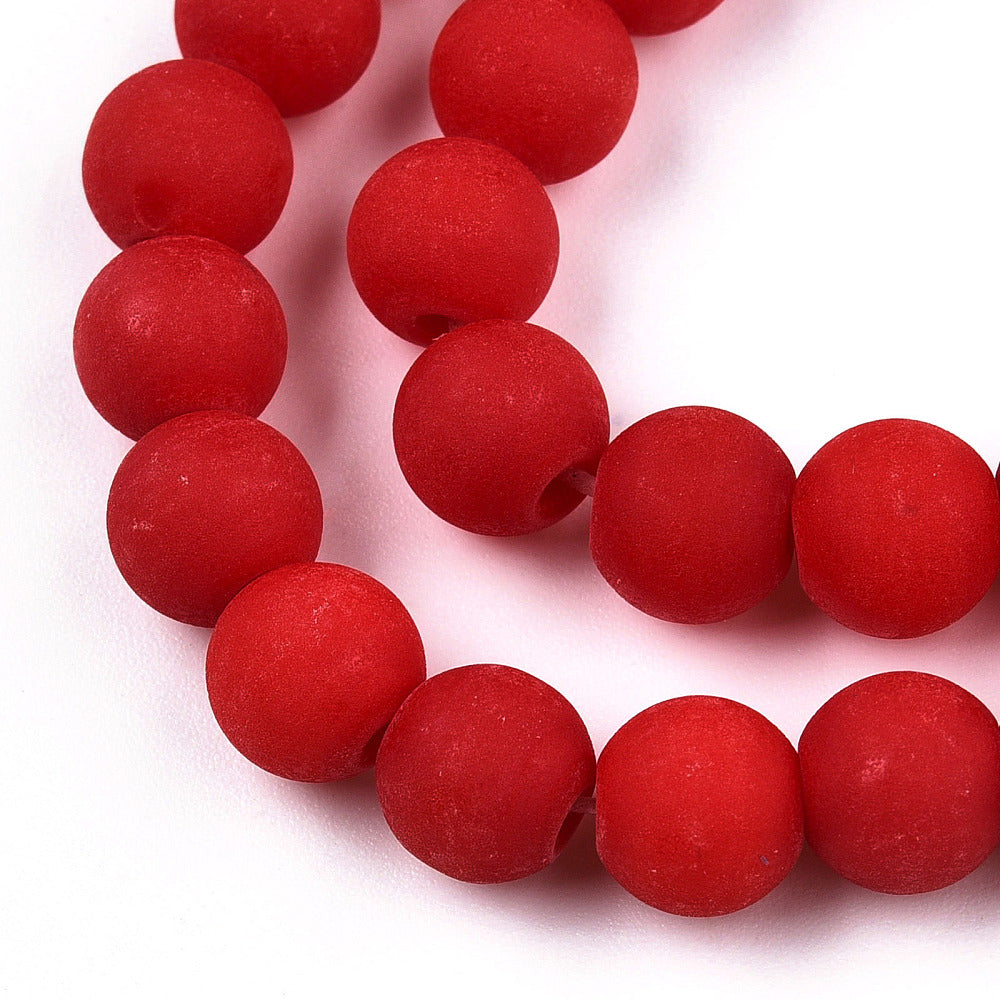 zoomed in section of four matte frosted red opaque round glass beads over white background. 