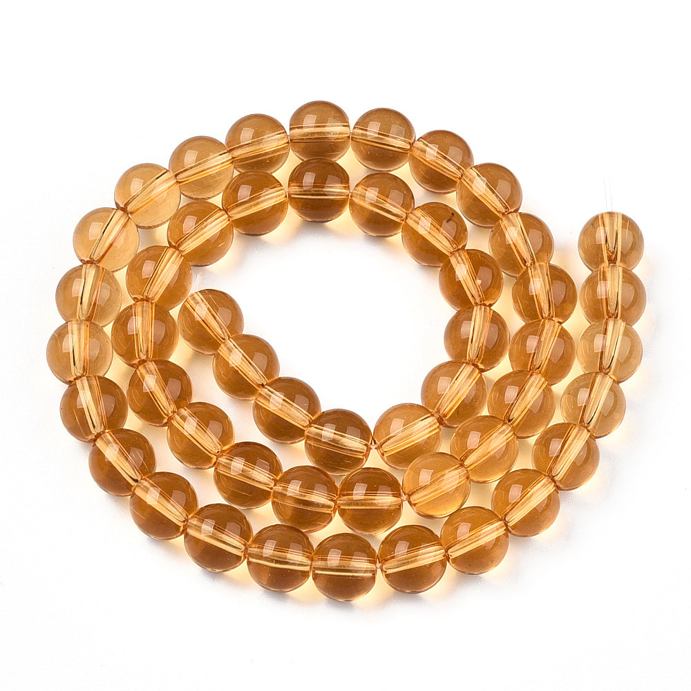 champagne colored round glass bead strand in a swirl design over white surface. 