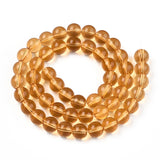 champagne colored round glass bead strand in a swirl design over white surface. 