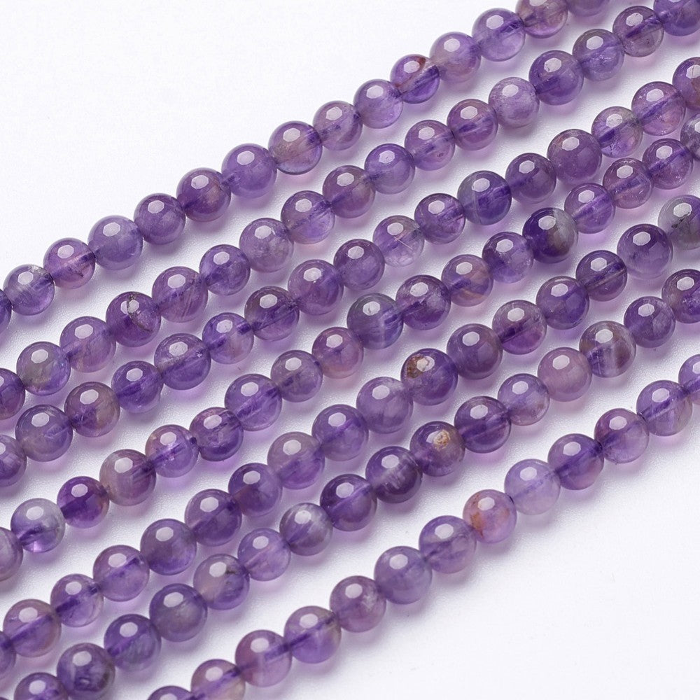 seven strands of smooth round amethyst beads over white background. 