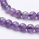 zoomed in section of two strands of smooth round amethyst beads over white background. 