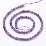 strand of smooth round amethyst beads in a spiral pattern over white background. 