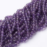 strands of smooth round amethyst beads twisted together over white background. 