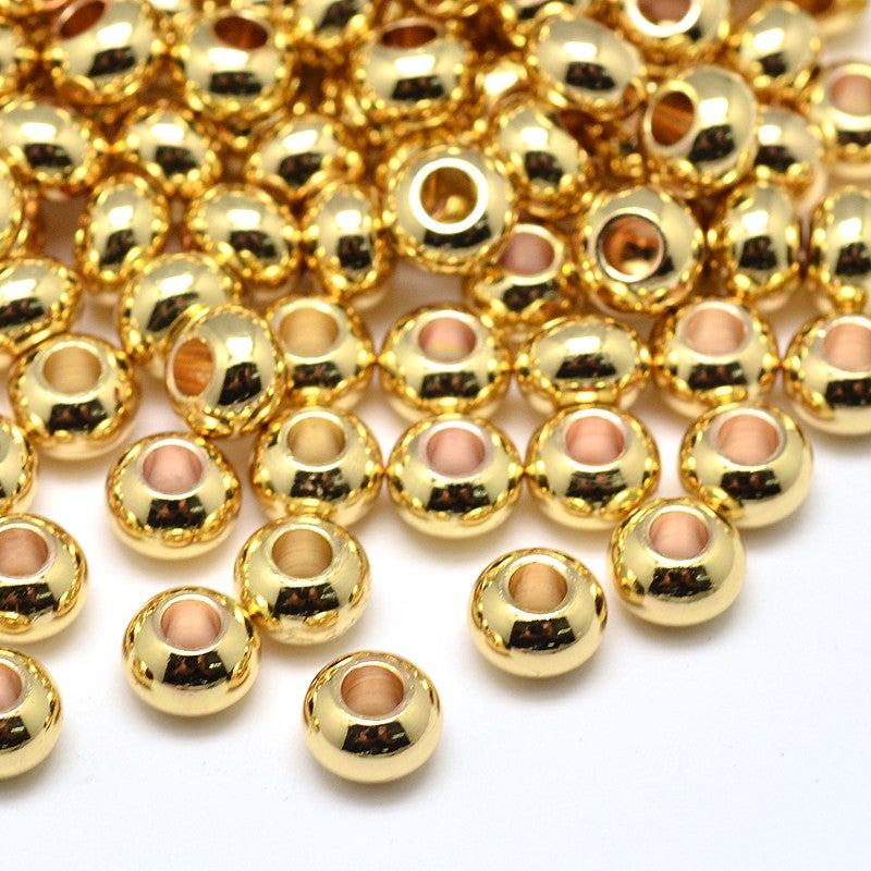 pile of light golden smooth rondelle spacer beads over white background. 
