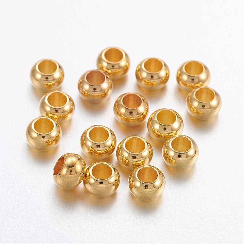 pile of golden smooth rondelle spacer beads over white background. 