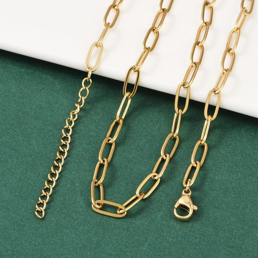 golden paperclip chain necklace with lobster claw clasp and extender chain draped over white ledge onto green felt surface. 