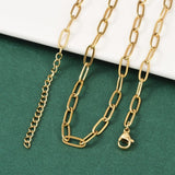 golden paperclip chain necklace with lobster claw clasp and extender chain draped over white ledge onto green felt surface. 