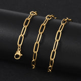 golden paperclip chain necklace with lobster claw clasp wrapped around black cylinder form with black background. 