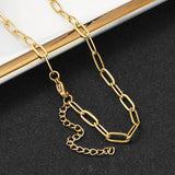 golden paperclip chain necklace with lobster claw clasp and extender chain draped over gold rimmed tray edge onto black textured surface. 