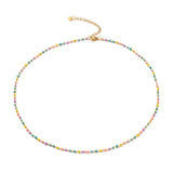 golden multi-color enamel twisted chain necklace with lobster claw clasp extender chain and cross charm over white background. 