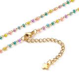 zoomed in sections of golden multi-color enamel twisted chain necklace with lobster claw clasp extender chain and cross charm over white background. 