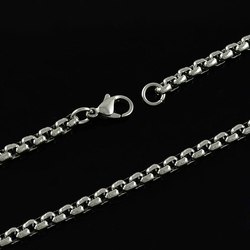 zoomed in sections of silver tone Venetian box chain necklace with lobster claw clasp over black background. 