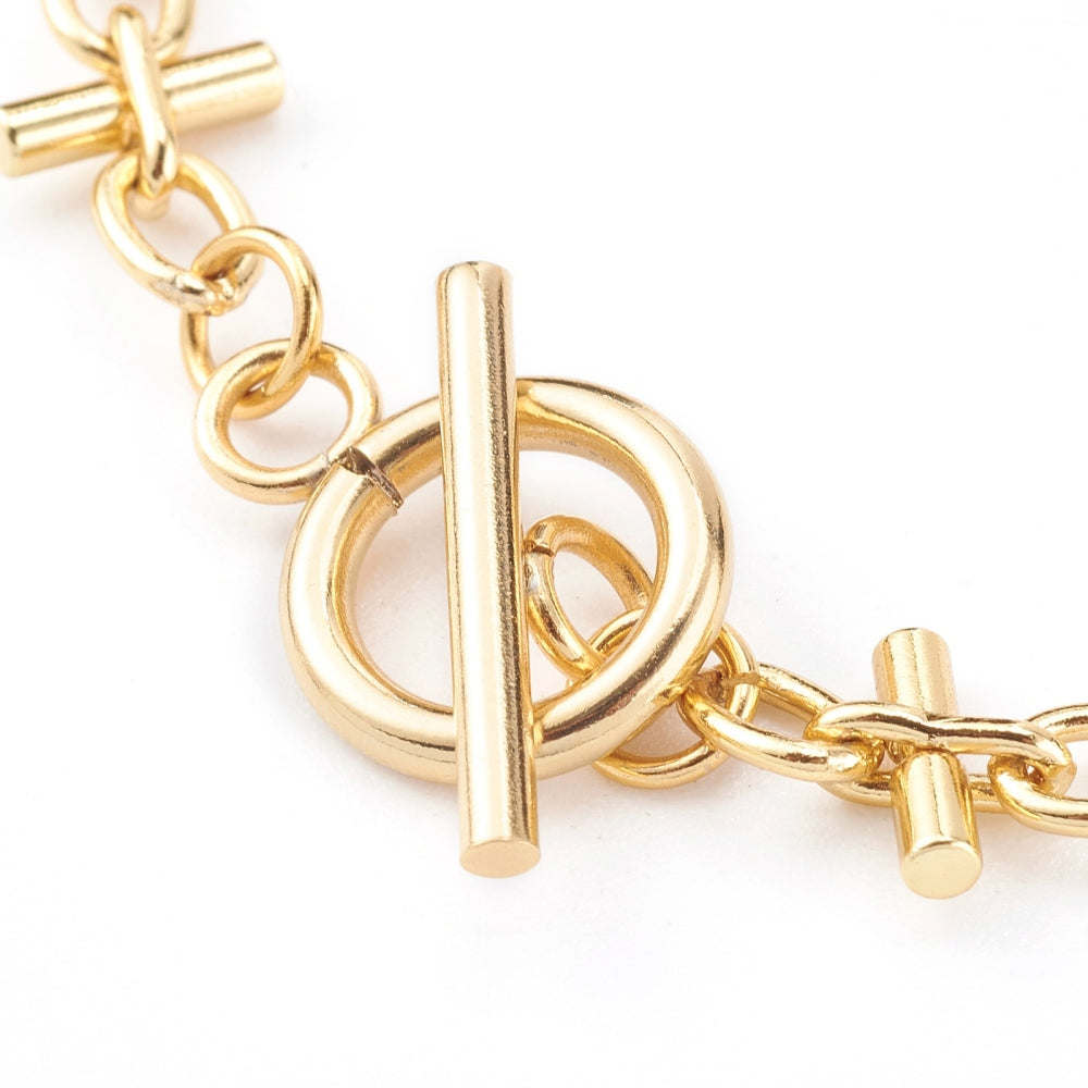 zoomed in section of golden bar link  bracelet with toggle clasp on a white background.