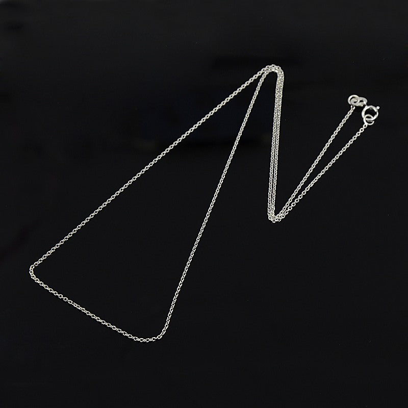 silver fine cable chain with spring ring clasp on black background. 