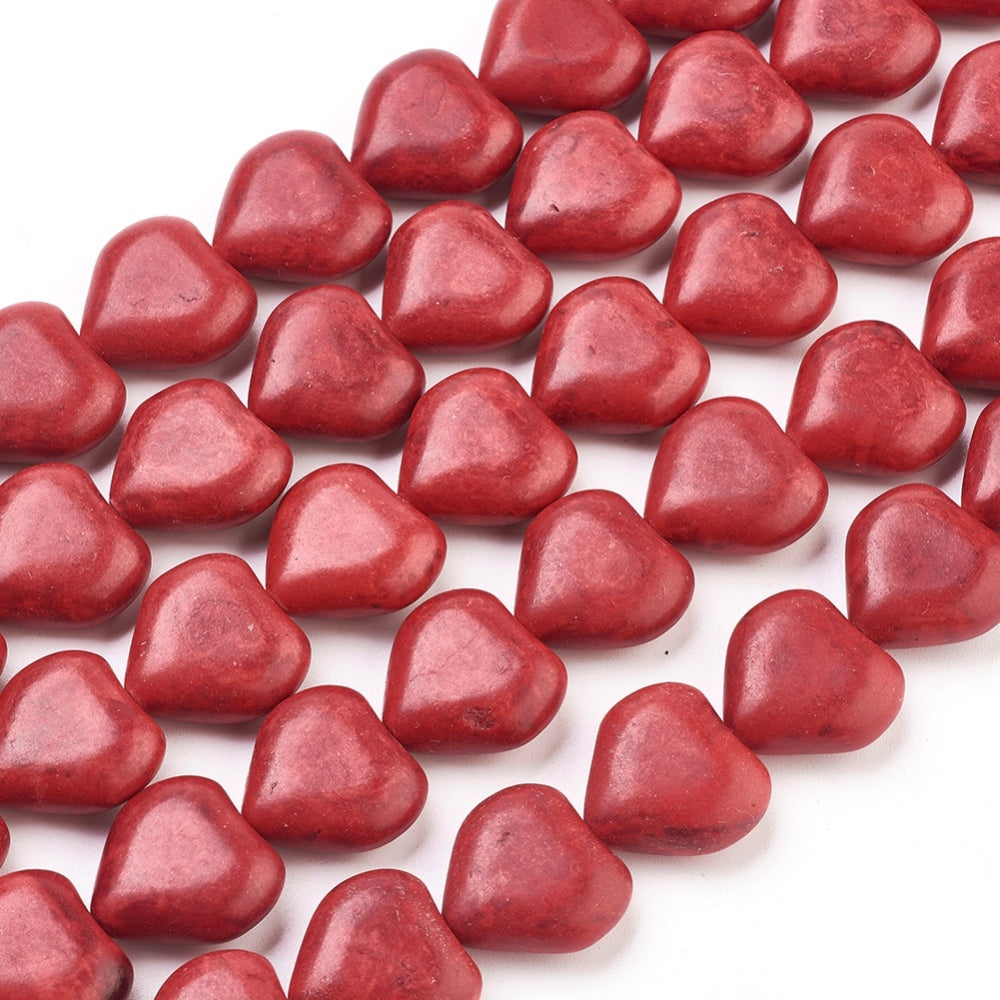 zoomed in sections of dyed red howlite heart bead strands over white surface. 