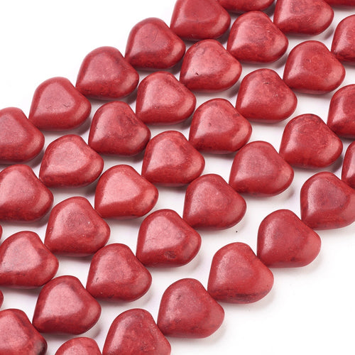 zoomed in sections of dyed red howlite heart bead strands over white surface. 