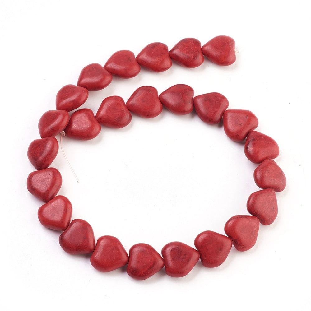 dyed red howlite heart bead strand in a swirl display over white surface. 