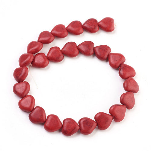 dyed red howlite heart bead strand in a swirl display over white surface. 