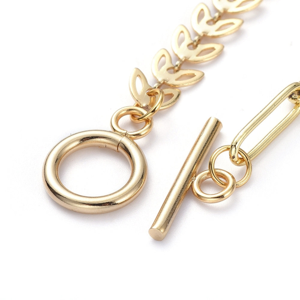 zoomed in golden toggle clasp on cob leaf and paperclip link mixed chain necklace on white background. 