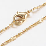 zoomed in sections of golden flattened link curb chain necklace with lobster claw clasp on a white background. 