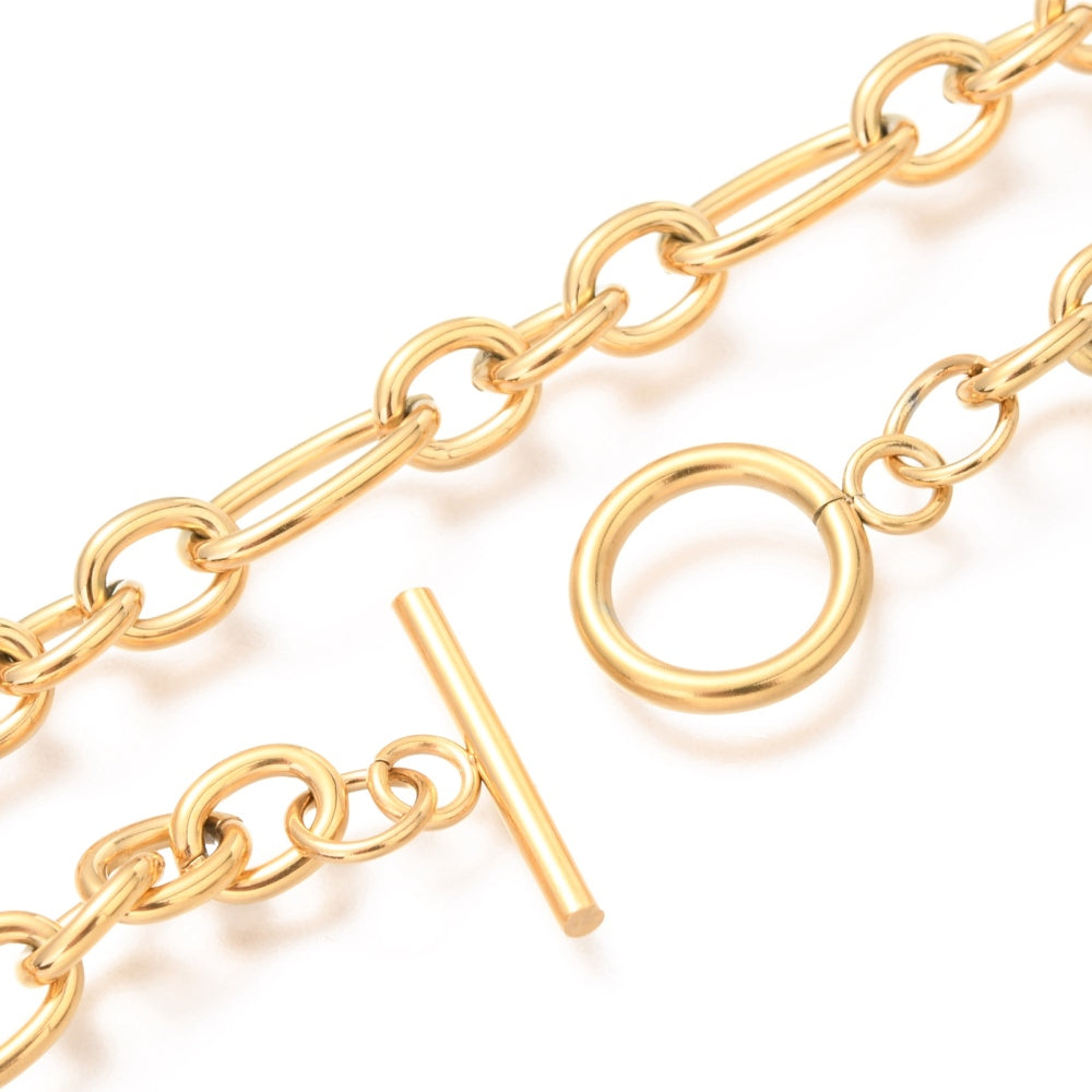 zoomed in section of golden Figaro chain necklace with toggle clasp on a white background.