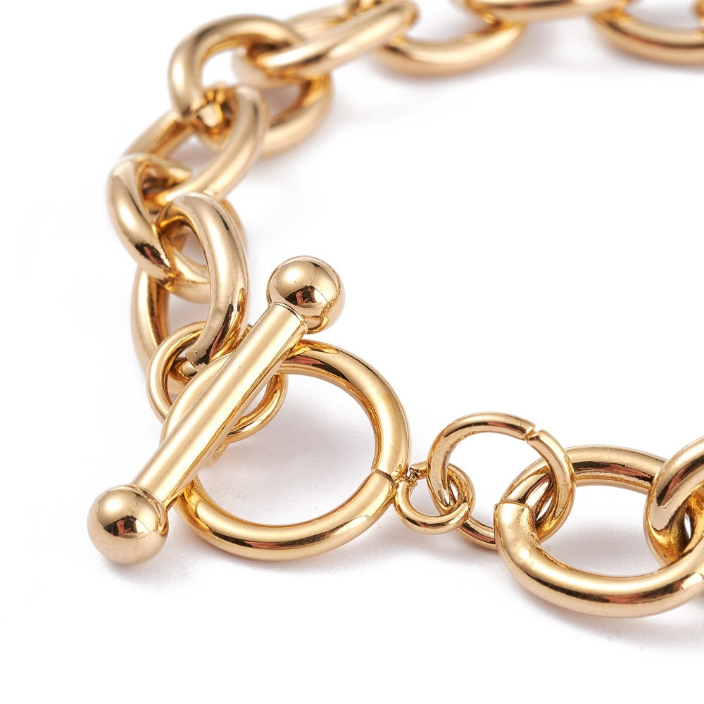 zoomed in golden toggle clasp on golden charm bracelet on a white background. 
