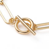 zoomed in golden toggle clasp on paperclip chain on white background. 