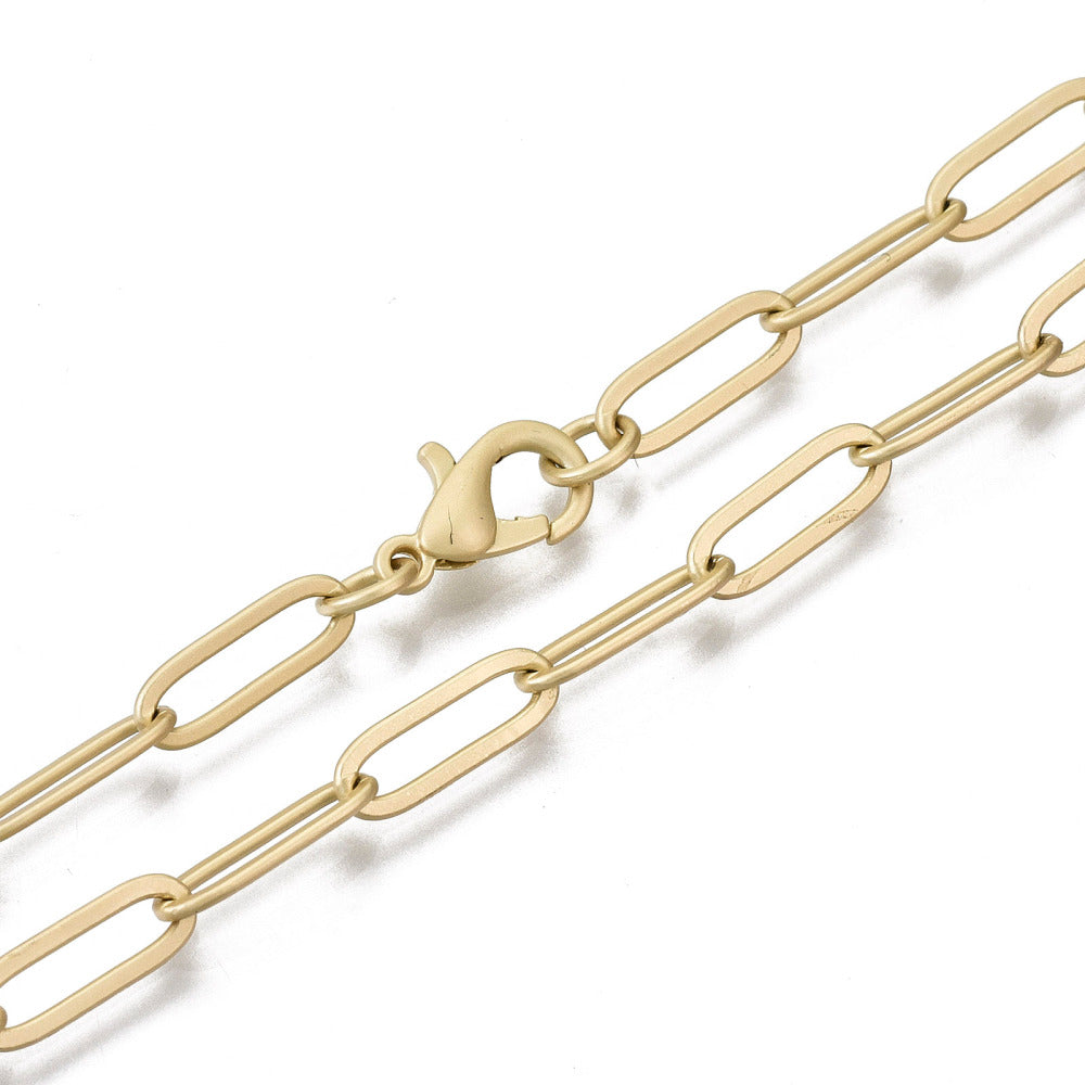 zoomed in sections of matte golden large paperclip link necklace with lobster claw clasp on white background. 