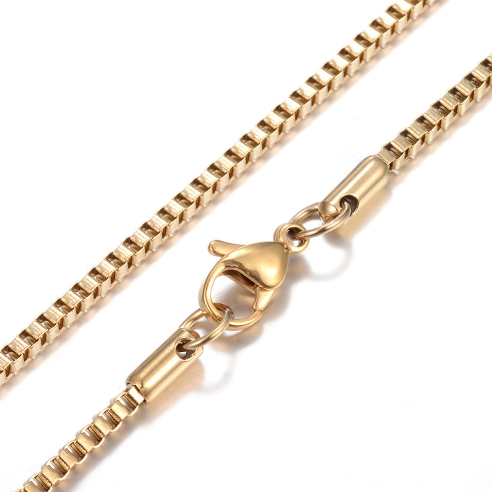 zoomed in sections of golden box chain necklace with lobster claw clasp on white background. 