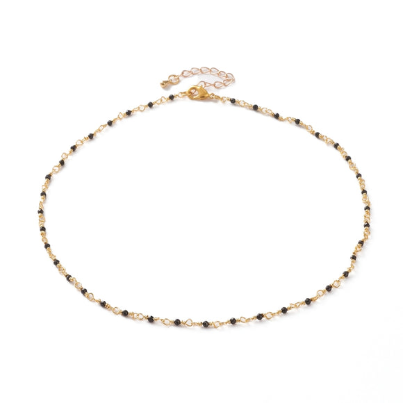 golden chain and black spinel faceted round beaded necklace with golden lobster claw clasp and extender chain over white background. 