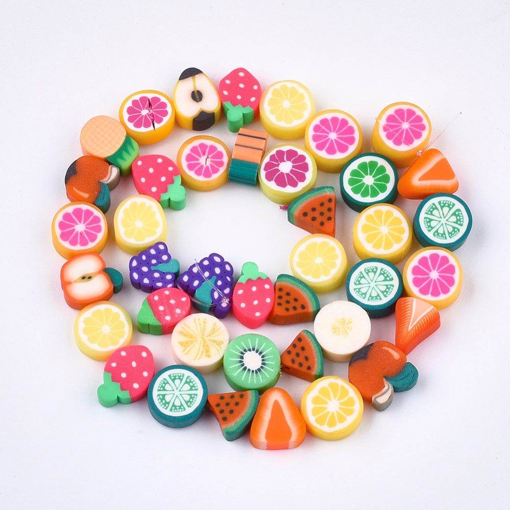 handmade polymer clay fruit bead strand in swirl display over white background. 
