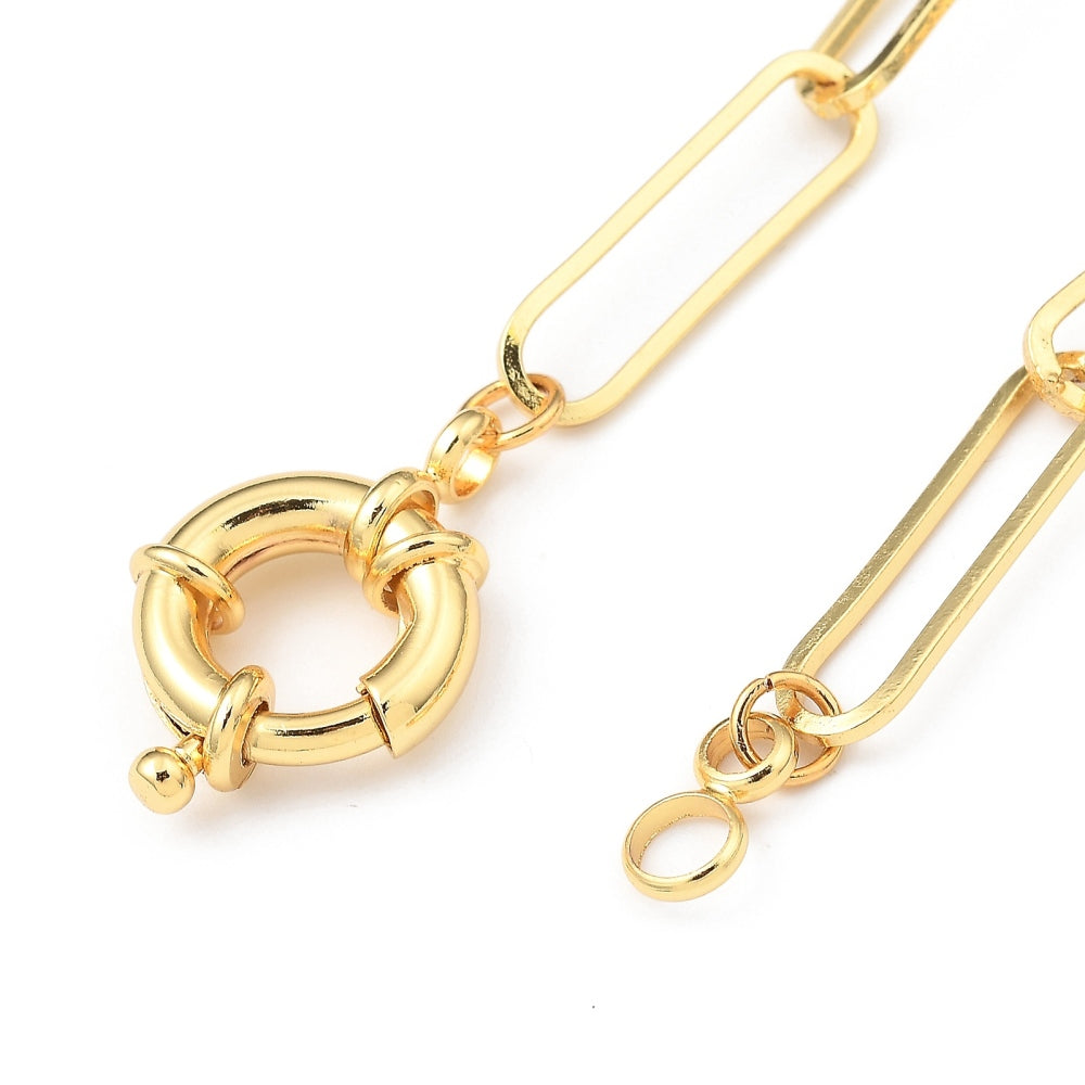 zoomed in section of large spring ring clasp on golden paperclip chain over  white background. 