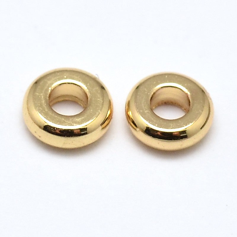 two golden rondelle spacer beads over white background. 