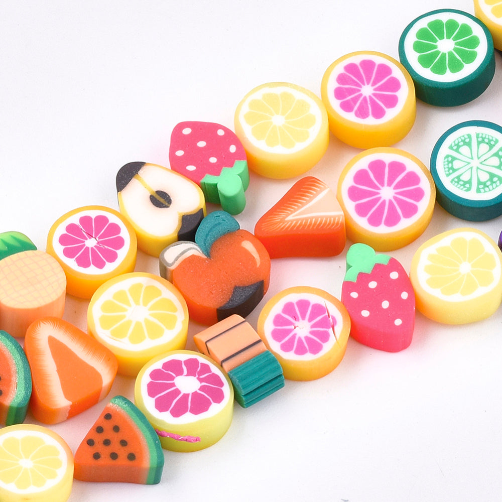 zoomed in sections of handmade polymer clay fruit bead strands over white background. 