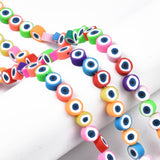 three multicolor polymer clay round eye bead strands draped over white cylinder form over white surface. 