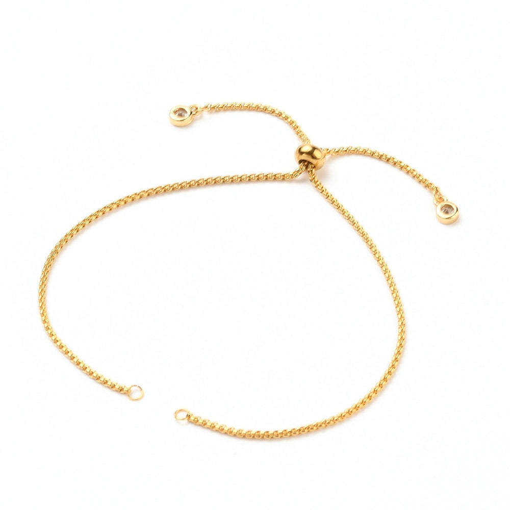 golden Bolo style bracelet making with slider bead and bezel set clear stone stopper beads on a white background. 